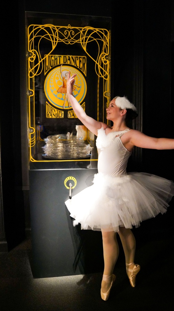 A young ballet dancer in a white tutu stand in front of a new exhibit called Light Dancer at Camera Obscura