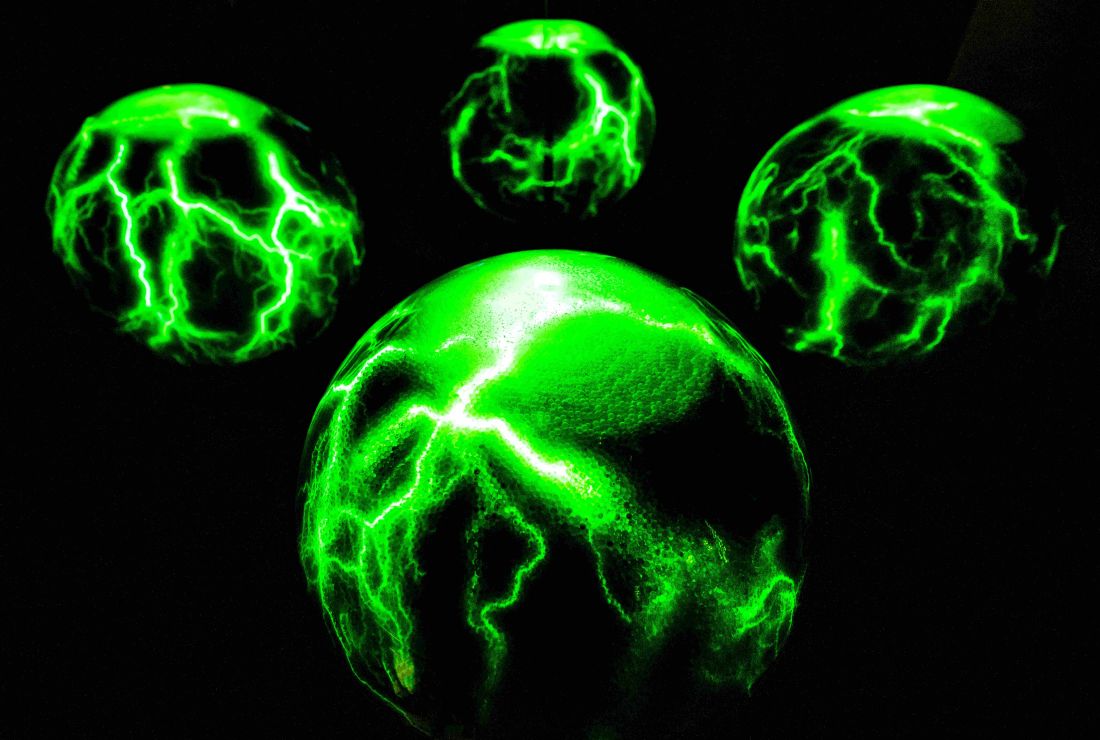 A green ball crackles with lines of electricity in a black room at Camera Obscura