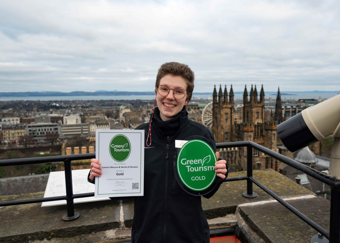 Staff member Phillipa with the award for Green Tourism Gold on the rooftop at Camera Obscura