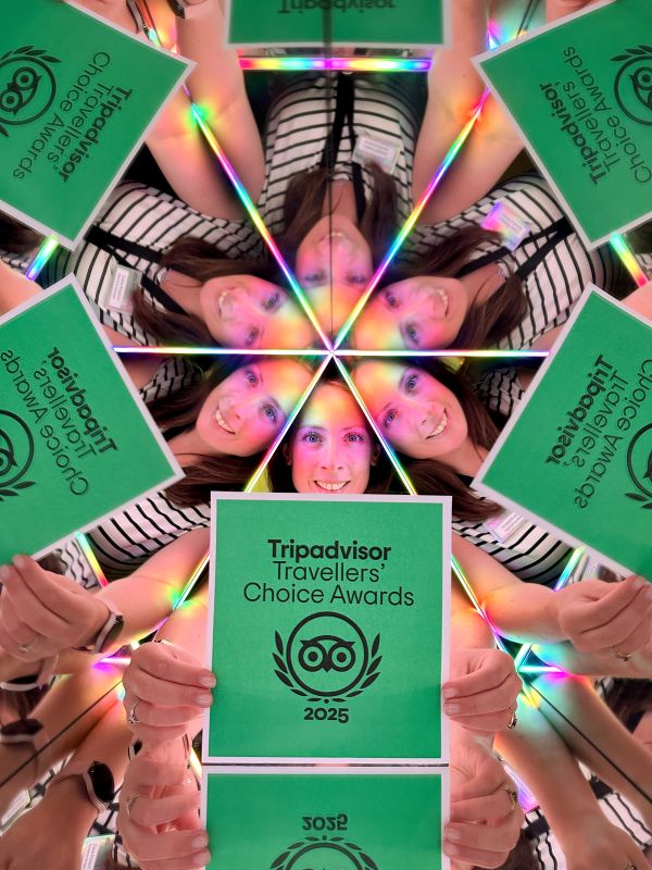 A member of staff with the Tripadvisor Travellers Choice Award in a colourful mirrored box at Camera Obscura