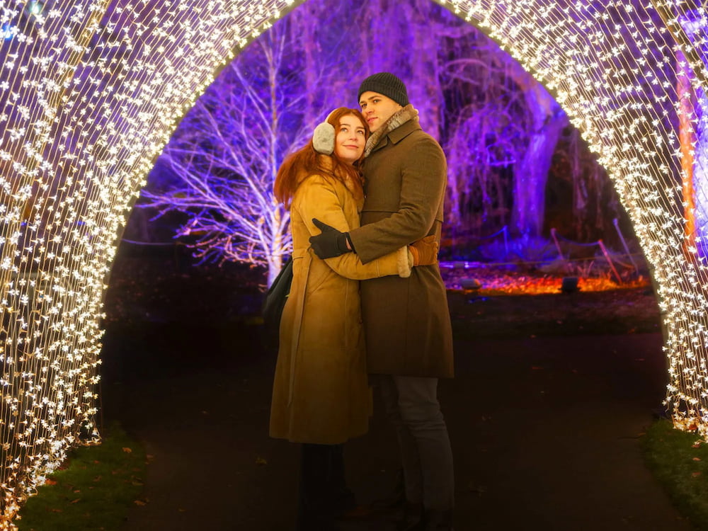 A couple stand under lights at the Edinburgh Botanic Gardens