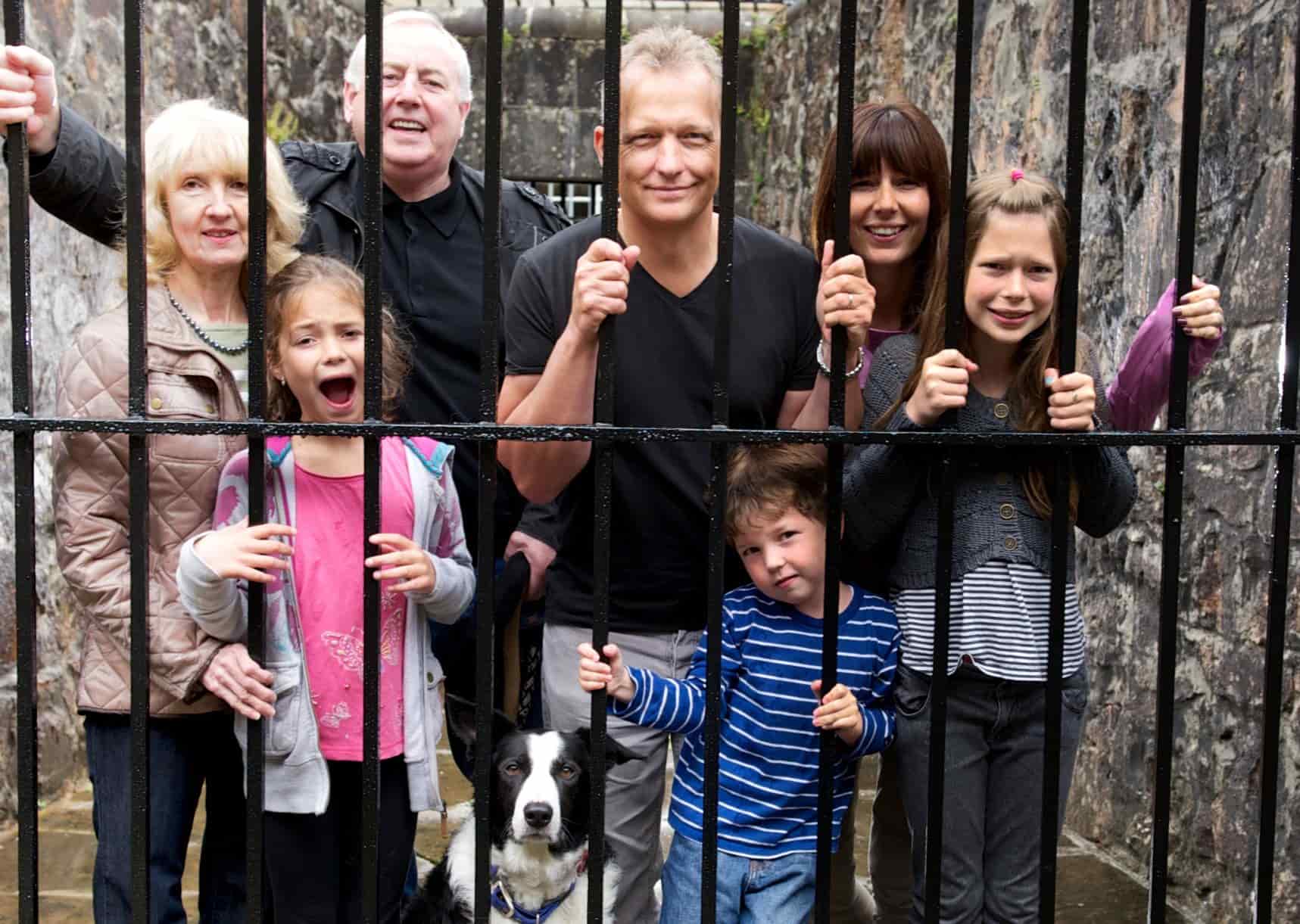 A family stand behind a metal gate at Inveraray Jail, Scotland