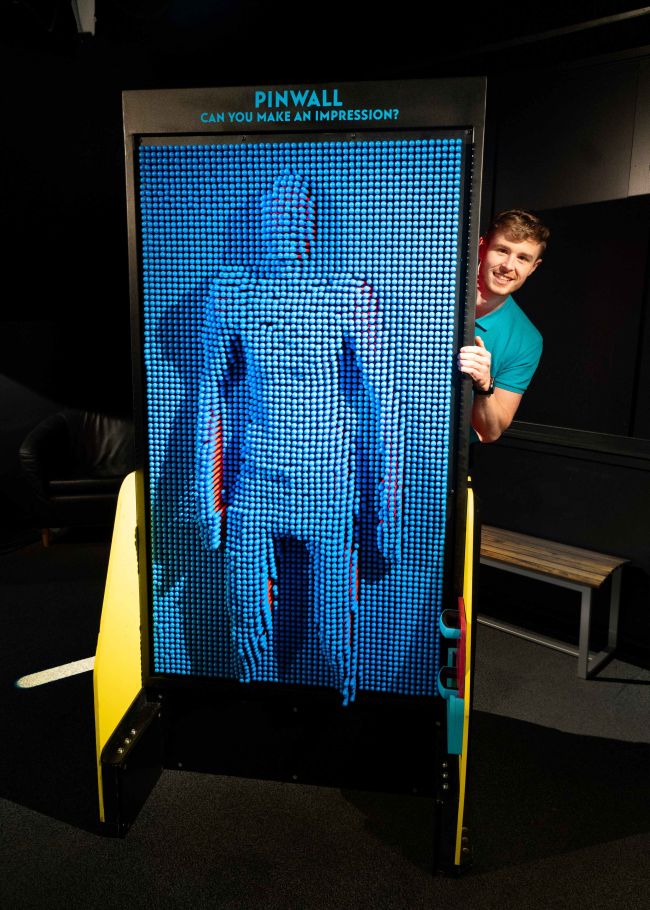 A guide stands at the Pinwall exhibit at Camera Obscura