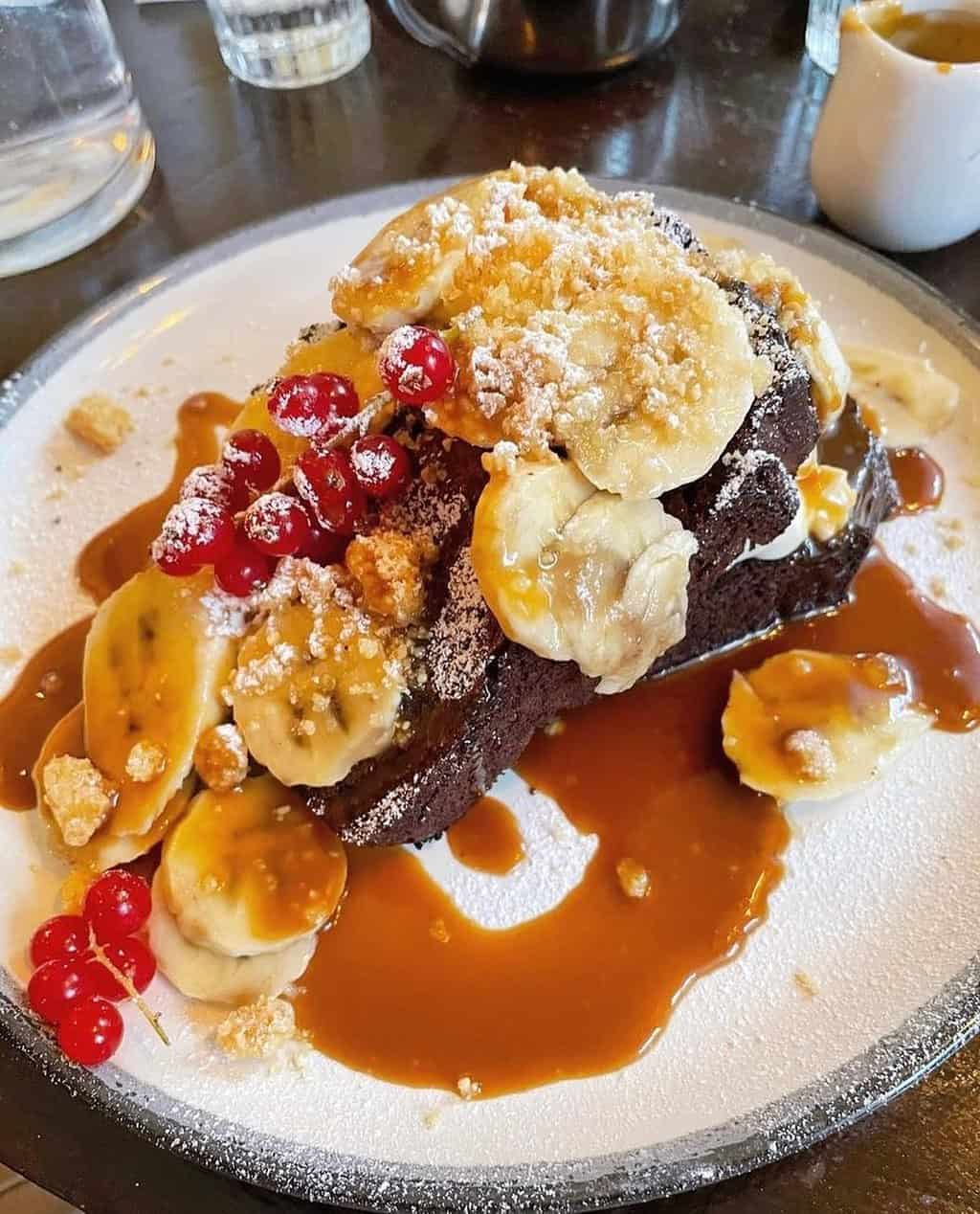 A breakfast plate of bananas, syrup and waffles