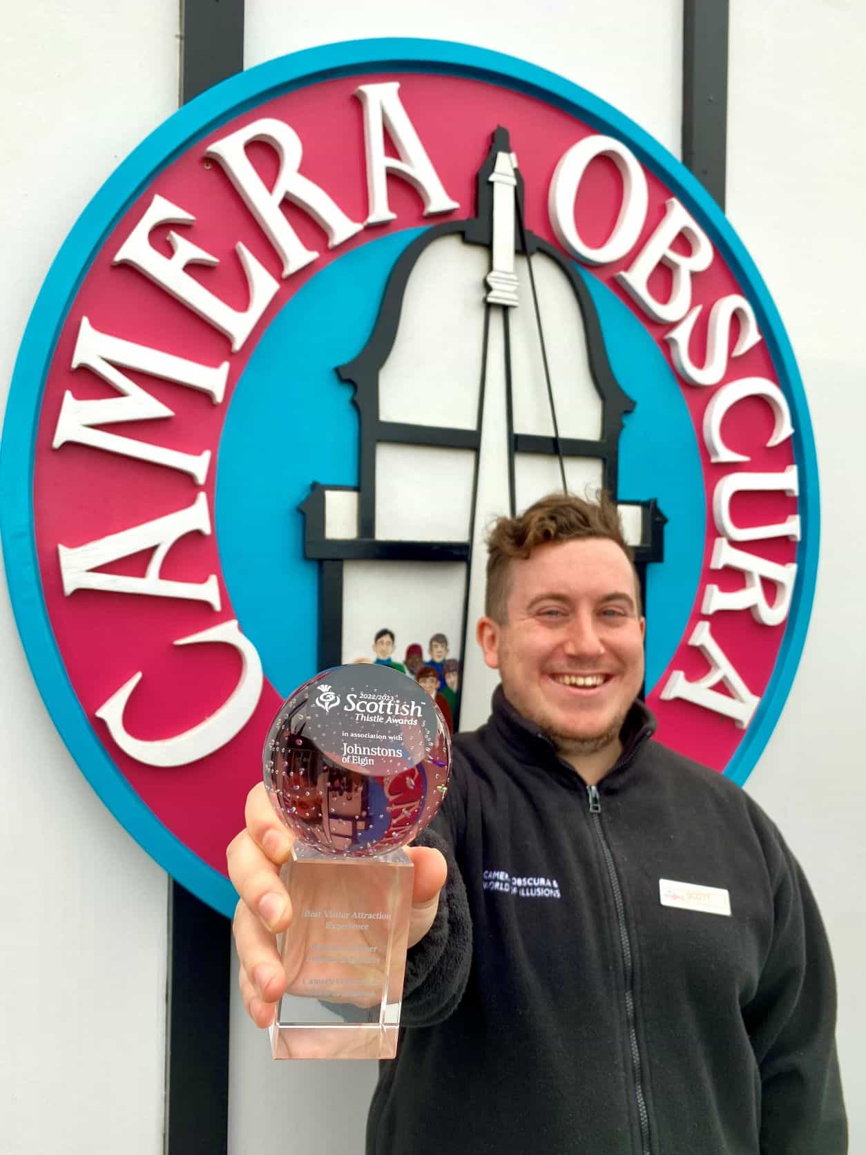 Team member Scott holds the glass Thistle Award