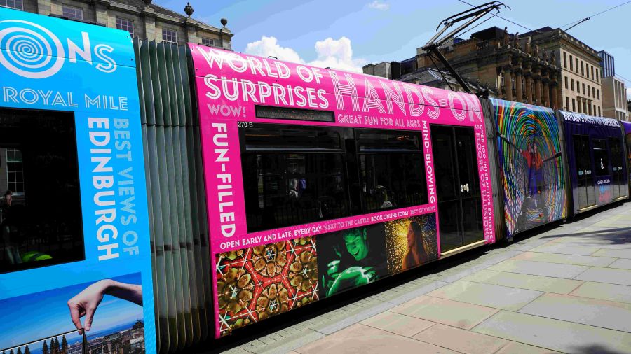 An Edinburgh tram brightly decorated with images of Camera Obscura & World of Illusions