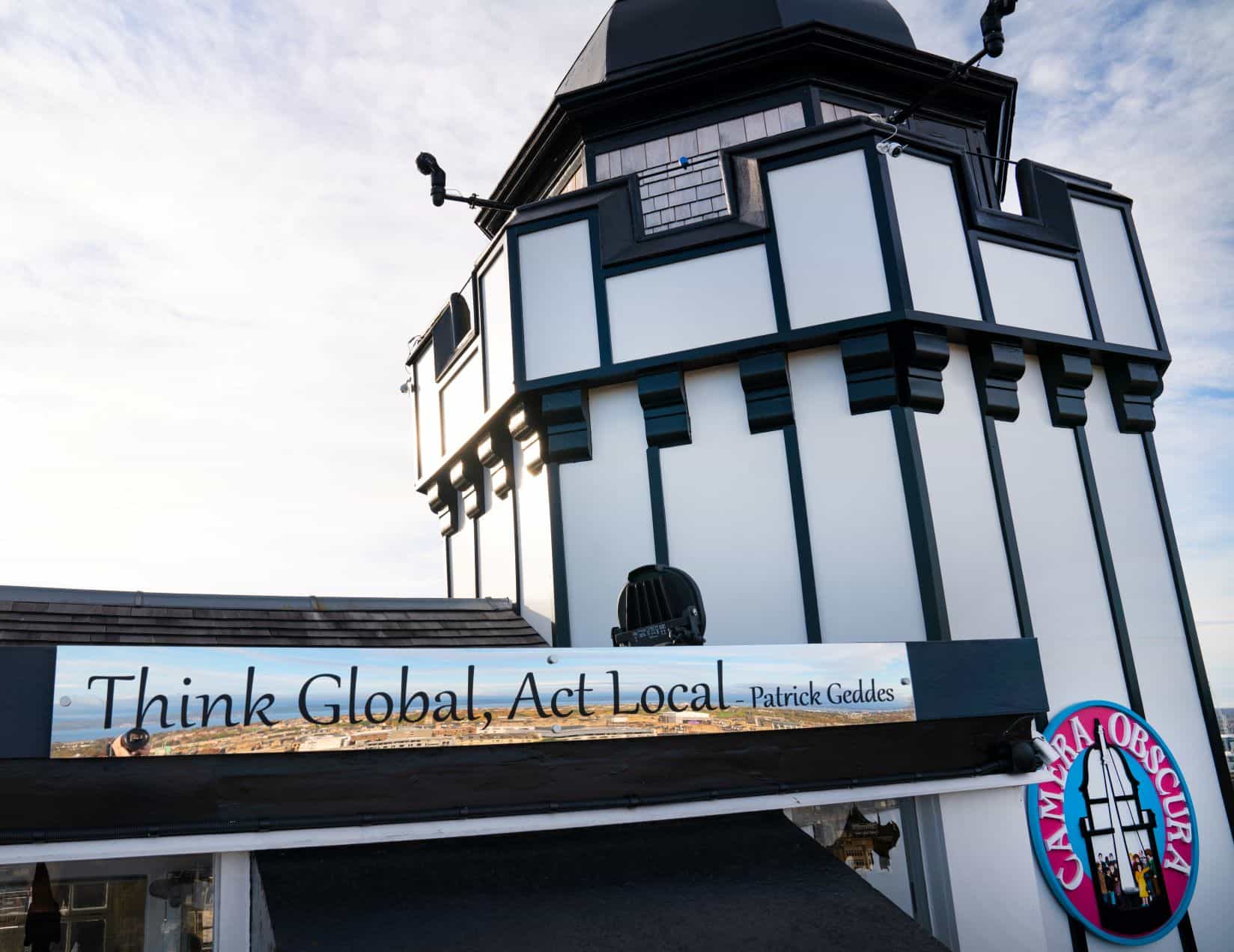 A sign on the rooftop at Camera Obscura with a Patrick Geddes quote 'Think Global, Act Local'