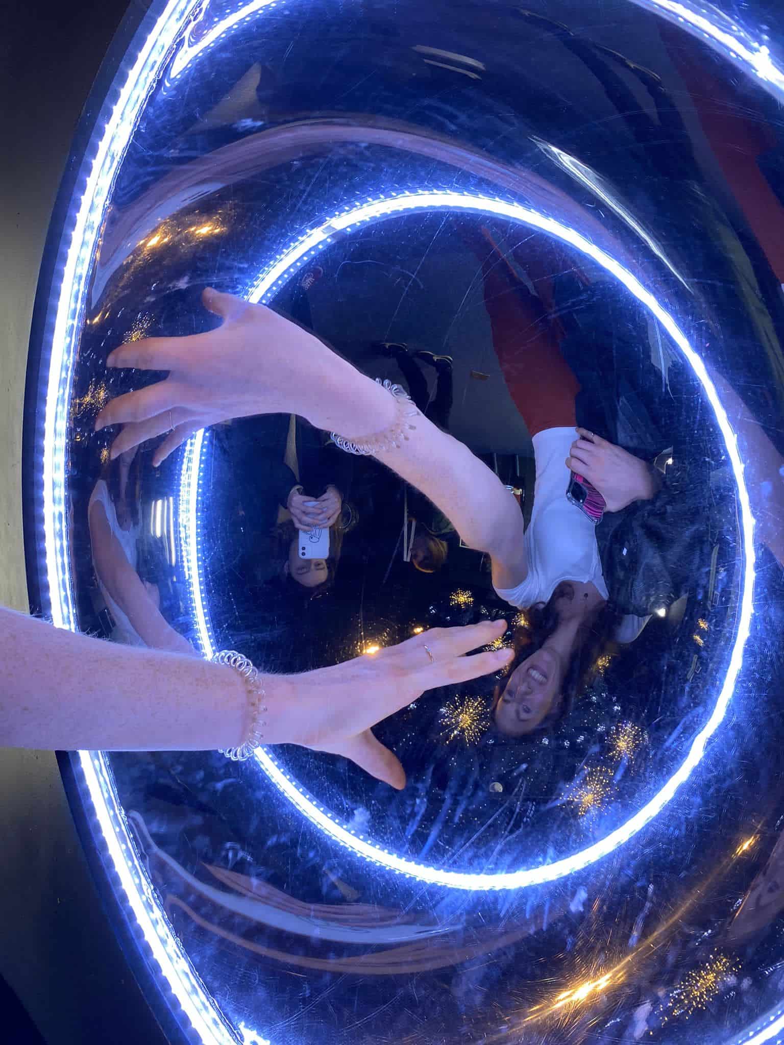 A hand reflected in reverse in a concave mirror at Landmark Forest Park