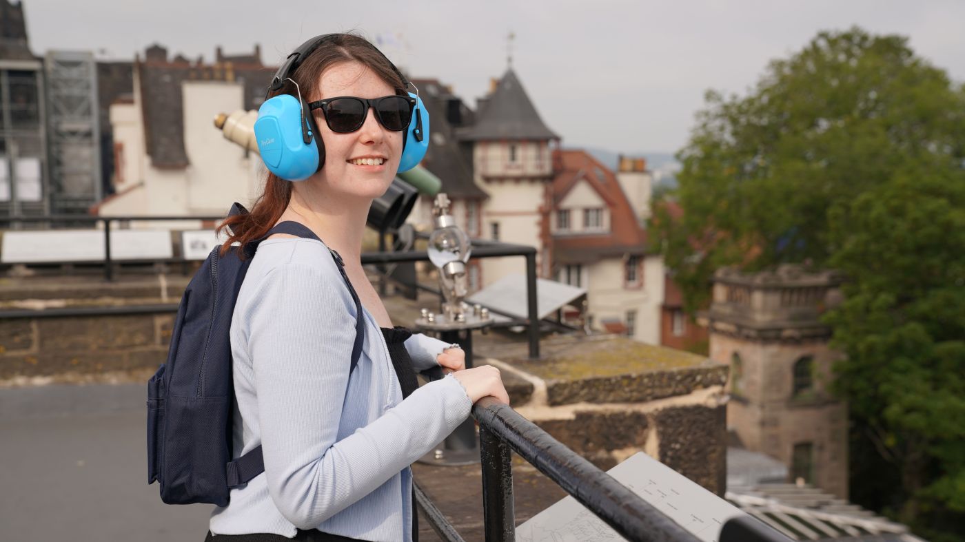 Girl on Rooftop Terrace at Camera Obscura with sunglasses, headphones and backpack